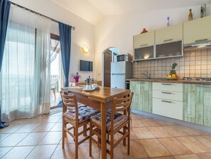 A kitchen with a dining table, chairs, a refrigerator, a microwave, and a tiled backsplash.