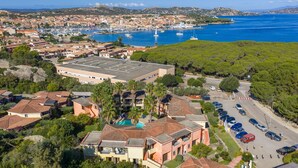 Vue aérienne d’une ville côtière avec des immeubles résidentiels, une marina et une mer d’un bleu limpide.