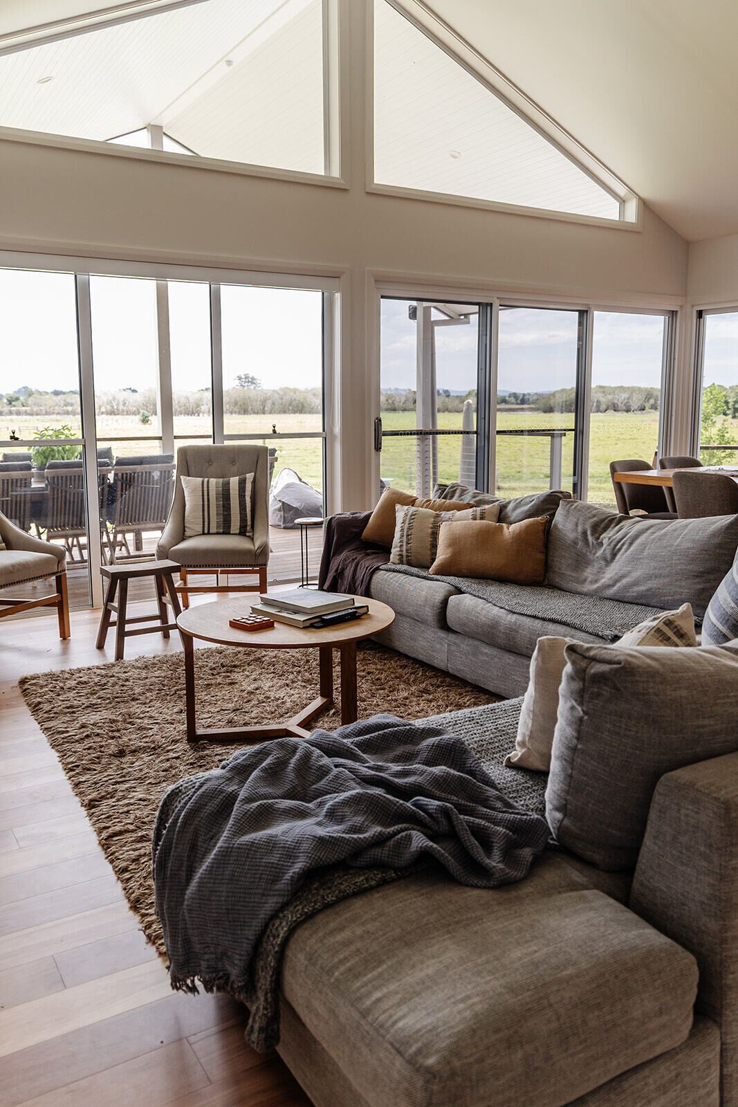 A spacious living room with a large sofa, a coffee table, and a dining area with chairs.
