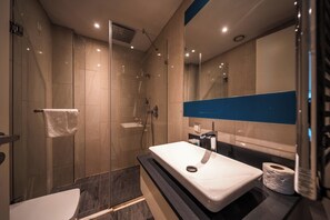 A modern bathroom with a glass-enclosed shower, a white sink, and a large mirror. - Petek Guest Teori (İstanbul)