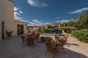 A patio with wicker furniture and a pool area. - Comfy Flat Immersed in Nature (Budoni)