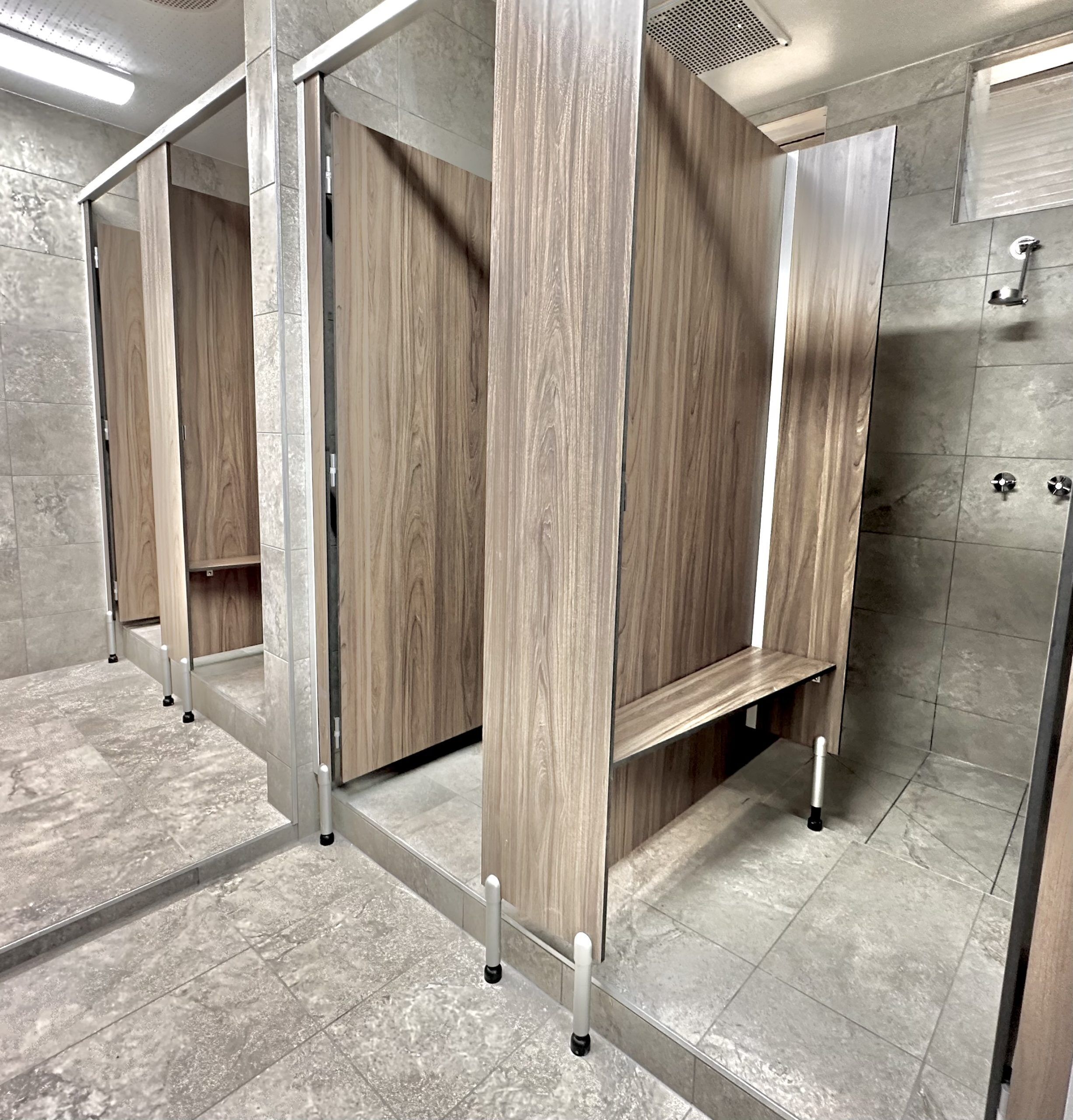 Un bagno moderno con divisori in legno e pavimento piastrellato.