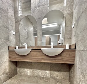 A modern bathroom with two sinks, wooden vanity, and large mirrors. - Mornington Peninsula Retro Caravans (Rye)
