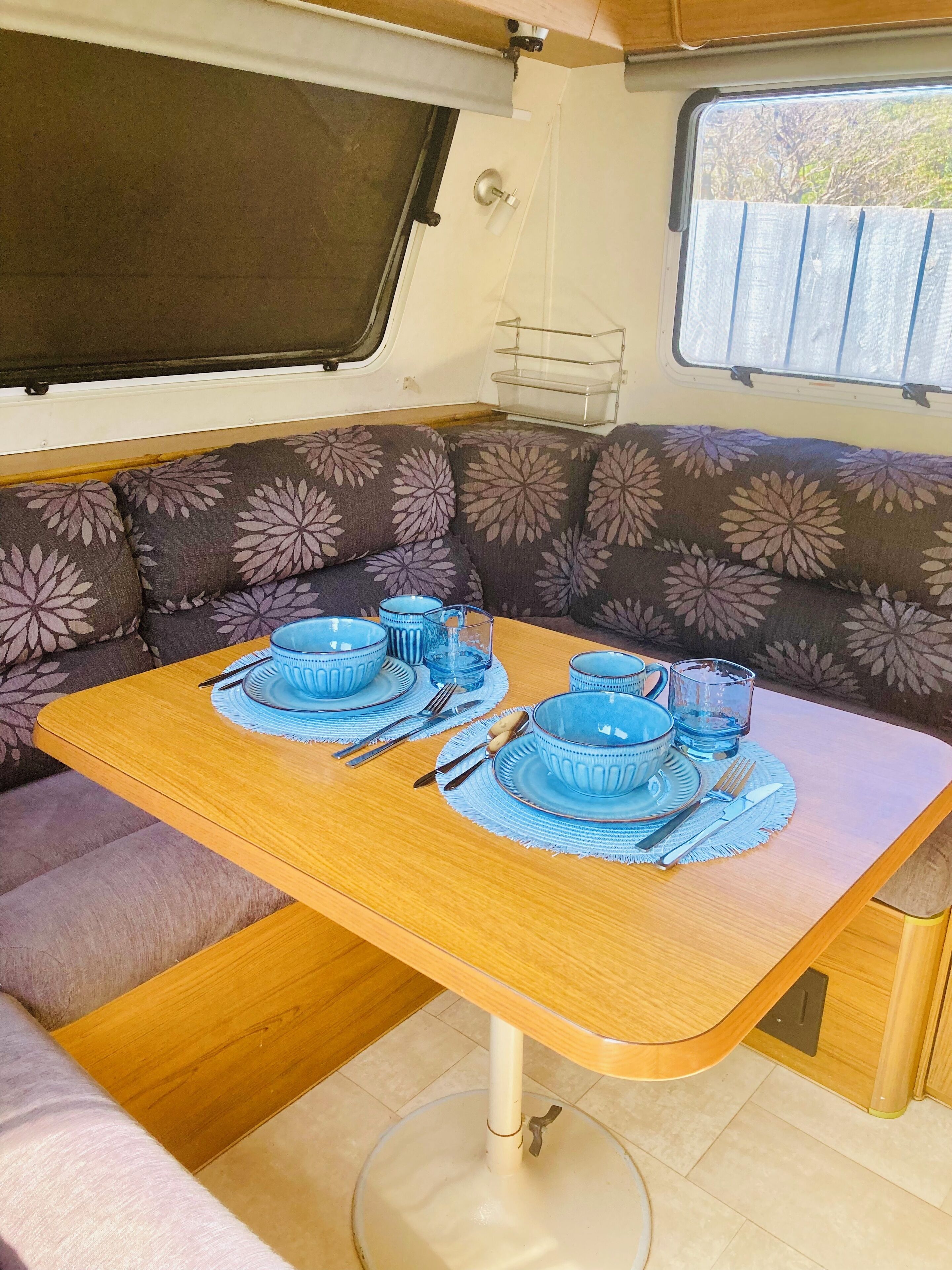 A dining area with a table set for four, surrounded by patterned cushions.