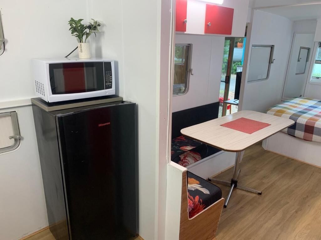 A compact kitchenette with a microwave, a small refrigerator, and a foldable table.
