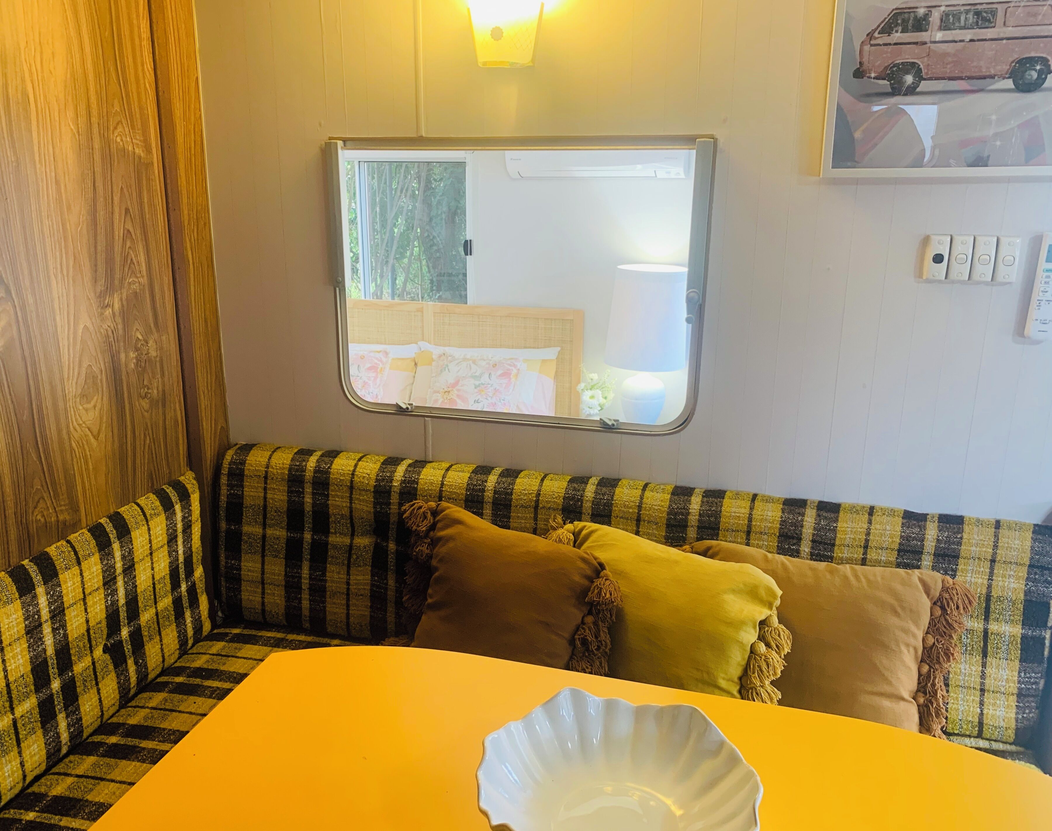 Un interior acogedor con un sofá a cuadros, una mesita y una ventana con vistas a la vegetación.
