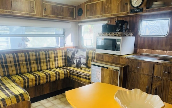 A compact RV kitchen with a microwave, coffee maker, and a sink. - Mornington Peninsula Retro Caravans (Rye)