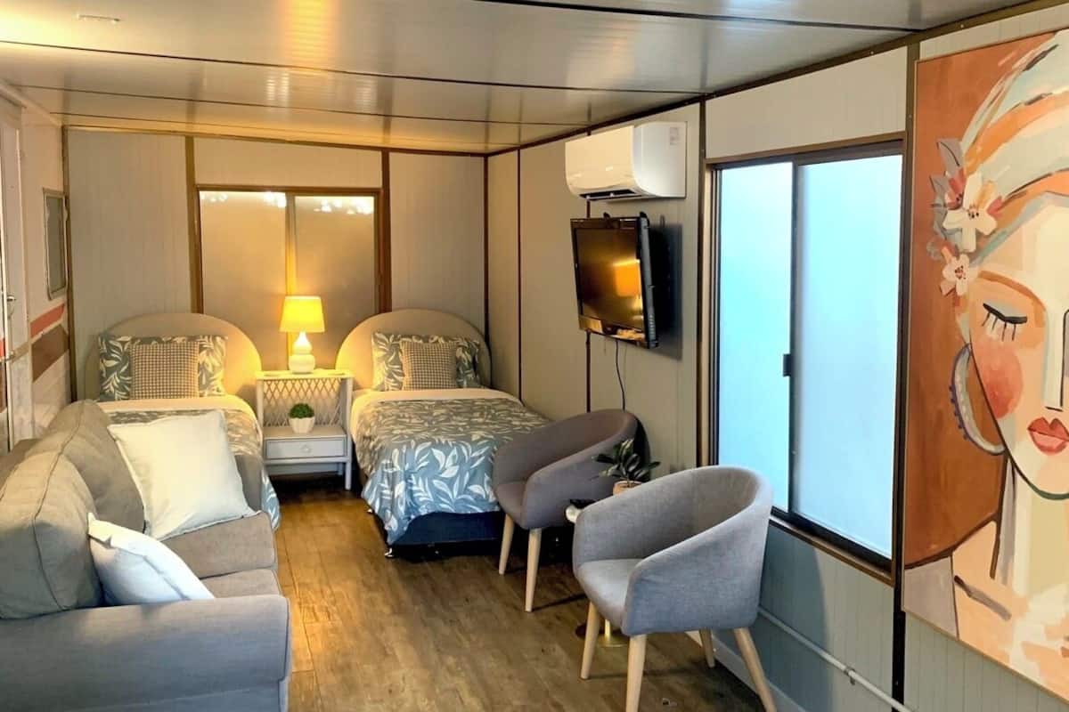 A compact room with a bed, two bedside tables with lamps, a TV, a sofa, and a chair.
