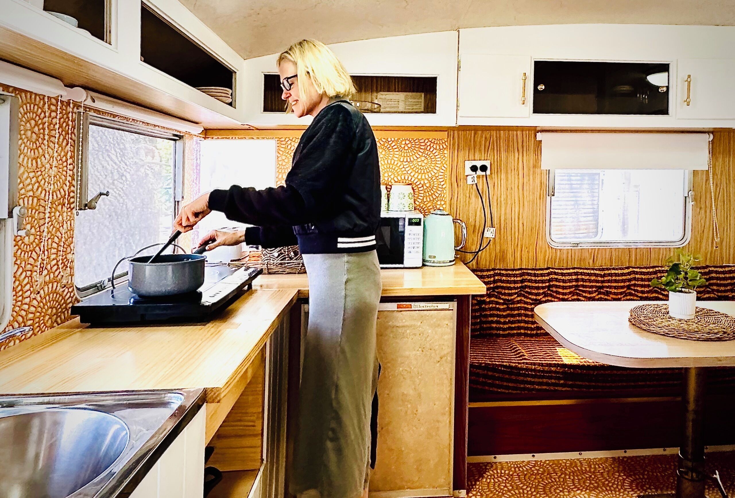 A compact kitchen with a stove, microwave, and sink.