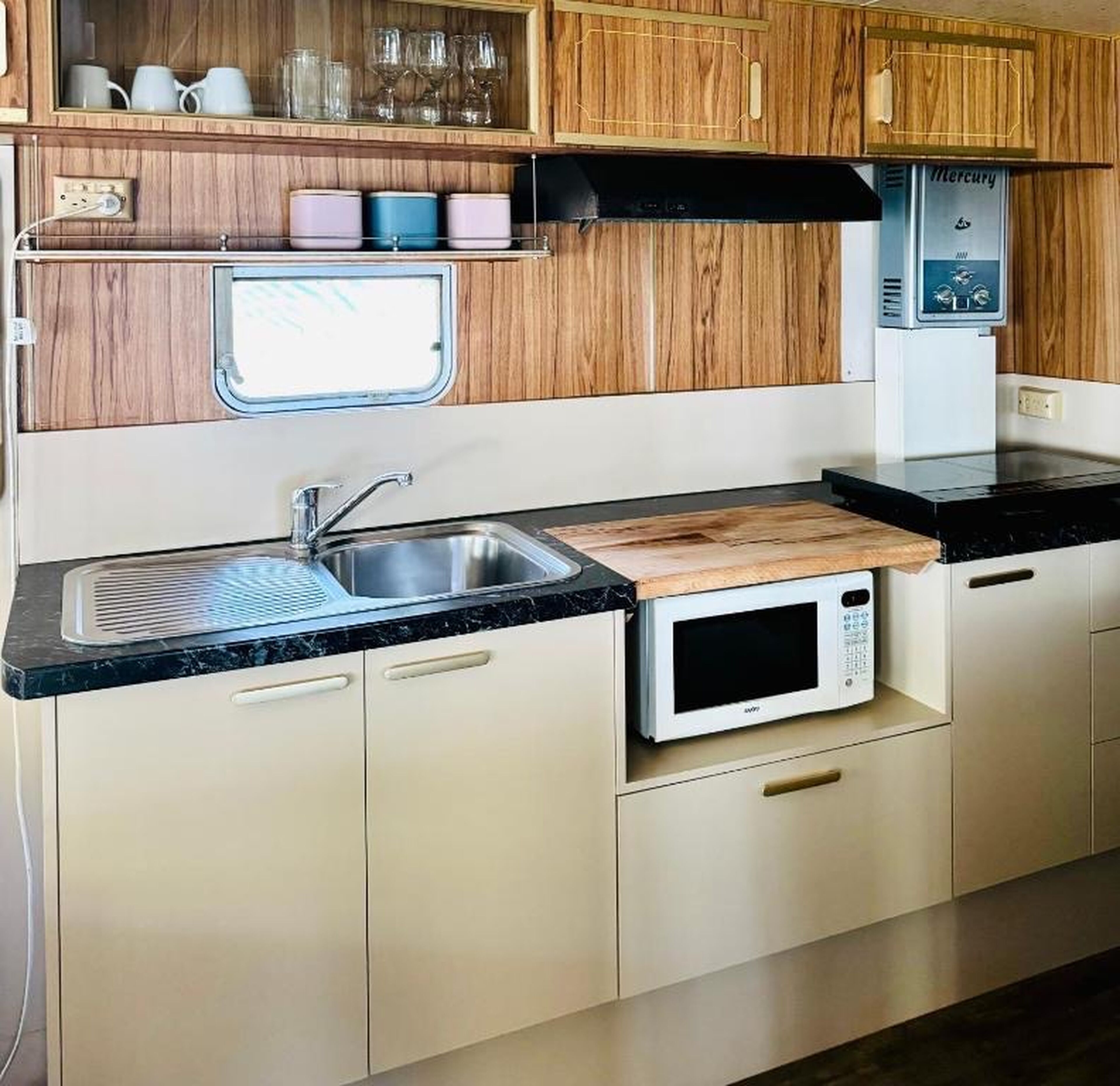 Cocina compacta con un fregadero, microondas y armarios de madera.