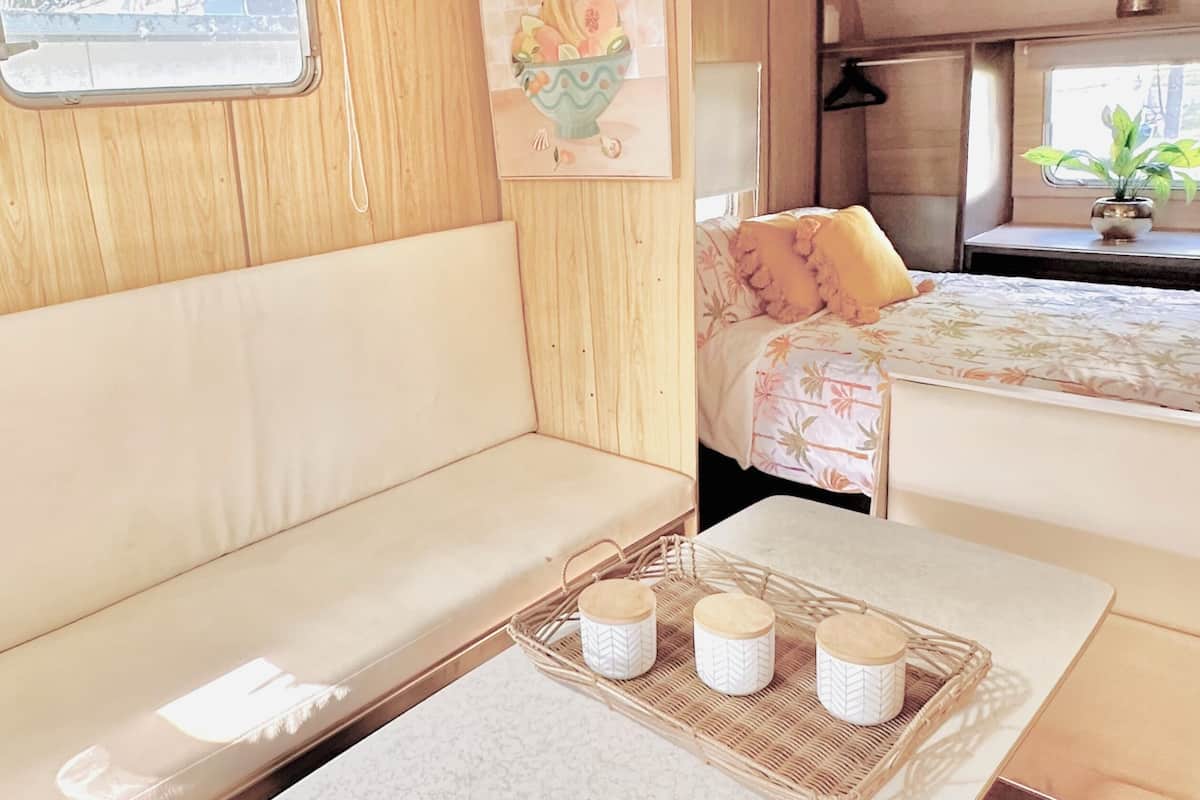 A cozy interior with a sofa, a small table with a tray, and a bed with a floral bedspread.