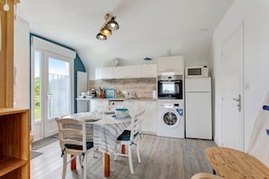 Een kleine keuken met een eettafel, stoelen, een wasmachine en een magnetron.