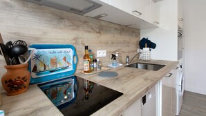 A modern kitchen with a wooden countertop, a built-in stove, a sink, and a dishwasher. - Studio "Port Lazo" with Sea View, Private Terrace and Wi-Fi (Plouézec)