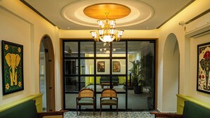 A lobby with a patterned floor, two green sofas, a chandelier, and artwork on the walls. - Hotel Indiana Hitech City (Hyderabad)