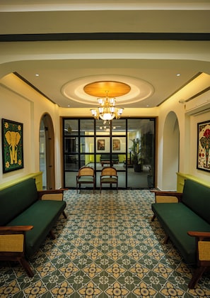 A lobby with a patterned floor, two green sofas, a chandelier, and artwork on the walls. - Hotel Indiana Hitech City (Hyderabad)
