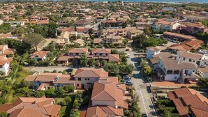An aerial view of a residential area with terracotta-roofed houses, a main road, and a mountain in the background. - Perfectly Located Flat in San Teodoro (San Teodoro)