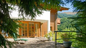 Eine moderne Außenpatio mit Steinboden, Holzmöbeln und Kübelpflanzen.