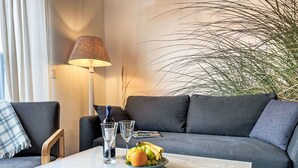 A modern living room with a grey sofa, a white coffee table, a lamp, and a potted plant. - Nice apartment for 2 people with WIFI, TV and terrace (Ostseebad Kühlungsborn)