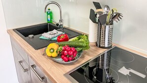 A kitchen with a black sink, stainless steel utensils, and fresh vegetables on the counter. - Nice apartment for 2 people with WIFI, TV and terrace (Ostseebad Kühlungsborn)