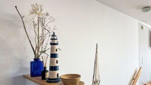 A wooden shelf with a decorative lighthouse, a blue vase with dried branches, and a macrame hanging. - Beautiful apartment for 6 people with WIFI, TV and patio (Ostseebad Kühlungsborn)