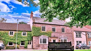 A traditional stone building with a brick facade, ivy-covered walls, and a central entrance with a door and windows.