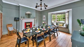 A dining room with a fireplace, a large window, and a ceiling fan.