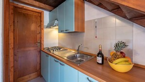 Une cuisine avec un plan de travail en bois, une cuisinière à gaz, un évier et un saladier rempli de fruits.