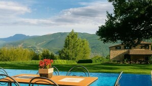 A pool with a table and chairs, surrounded by greenery and mountains. - VILLA NASCA - Ville Carborello (Castelraimondo)
