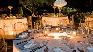 A formal outdoor dining setup with round tables, clear chairs, and candlelit ambiance. - VILLA NASCA - Ville Carborello (Castelraimondo)