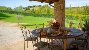 A round table with chairs, a stone pillar, and a view of a green landscape. - VILLA NASCA - Ville Carborello (Castelraimondo)