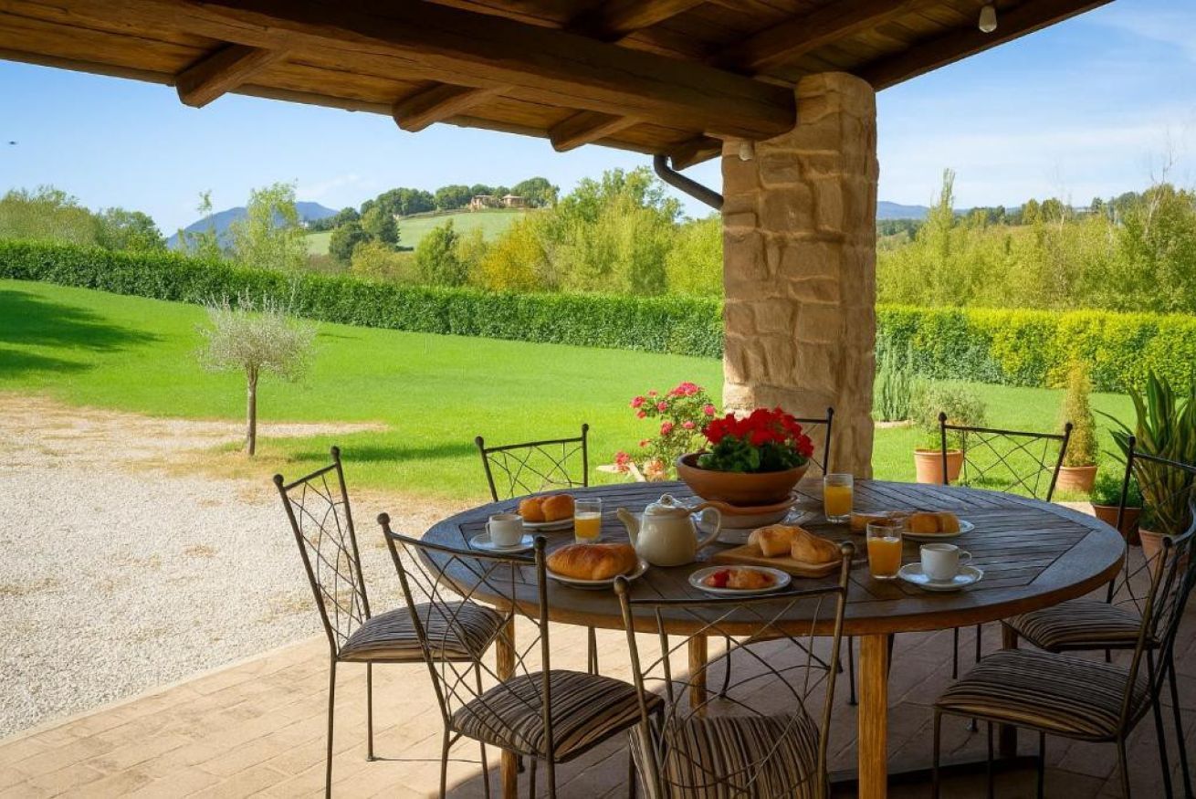 Un espace extérieur aménagé pour les repas, avec un pilier en pierre, une table ronde et des chaises.