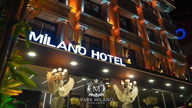 The exterior of the Milano Hotel with a prominent sign, classical architecture, and decorative statues at the entrance. - PARK MİLANO (Izmir)