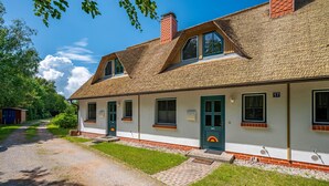 A two-story building with a thatched roof, a green door, and a number '17' sign. - Terraced house in a quiet location close to the beach (Wustrow)