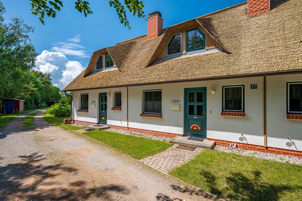 A two-story building with a thatched roof, a green door, and a number '17' sign. - Terraced house in a quiet location close to the beach (Wustrow)