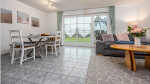 A dining area with a table and chairs, a sofa, and a window with a view of the outdoors. - Terraced house in a quiet location close to the beach (Wustrow)