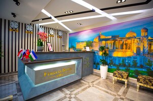 Un mostrador de recepción de hotel con relojes, banderas y un mural de un edificio.