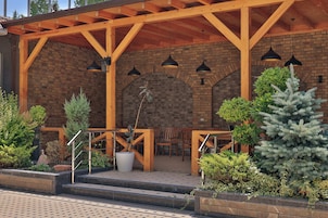 Un patio al aire libre con vigas de madera, paredes de ladrillo y plantas en macetas.