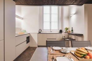A compact kitchen with a dining area, featuring a window, a sink, and a small countertop with a kettle and a bottle. - Apartment in Como with 2 bedrooms sleeps 4 (Como)