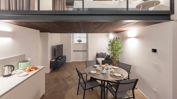 Ett modernt kök med en matplats, en tv och en växt.