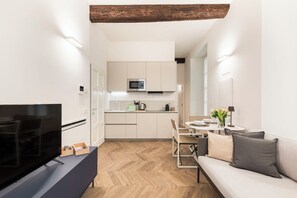 Ein modernes Wohnzimmer mit Flachbildfernseher, einer Couch und einem Essbereich mit Tisch und Stühlen.