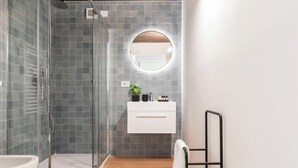 Et moderne badeværelse med glasbrusekabine, et hvidt spejlskab og en håndklædestang.