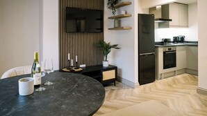 A modern kitchen with a built-in oven, a black refrigerator, and wooden shelves. - Sun St Apartment 2 (Lancaster)