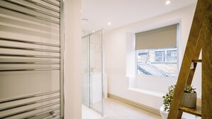 A modern bathroom with a glass shower enclosure, a white sink, and a window with a view of the outside. - Sun St Apartment 2 (Lancaster)