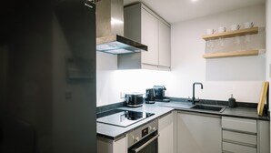 A modern kitchen with a built-in oven, a coffee maker, and a sink. - Sun St Apartment 2 (Lancaster)
