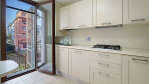 A kitchen with a view of a balcony, a gas stove, and cabinets. - Ca' Mercati Apartment with Two Bedrooms in Mestre Venice (Venezia)