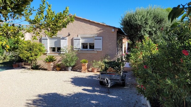 A house with a gravel driveway, potted plants, and a parked vehicle.