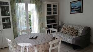 A living room with a round table, chairs, a sofa, and a bookshelf.