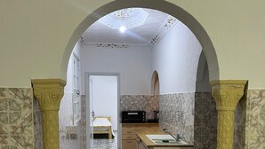 Un pasillo estrecho con piso estampado que conduce a un dormitorio y una zona de cocina.