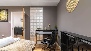 Een moderne slaapkamer met een bed, een bureau, een stoel en een open haard.