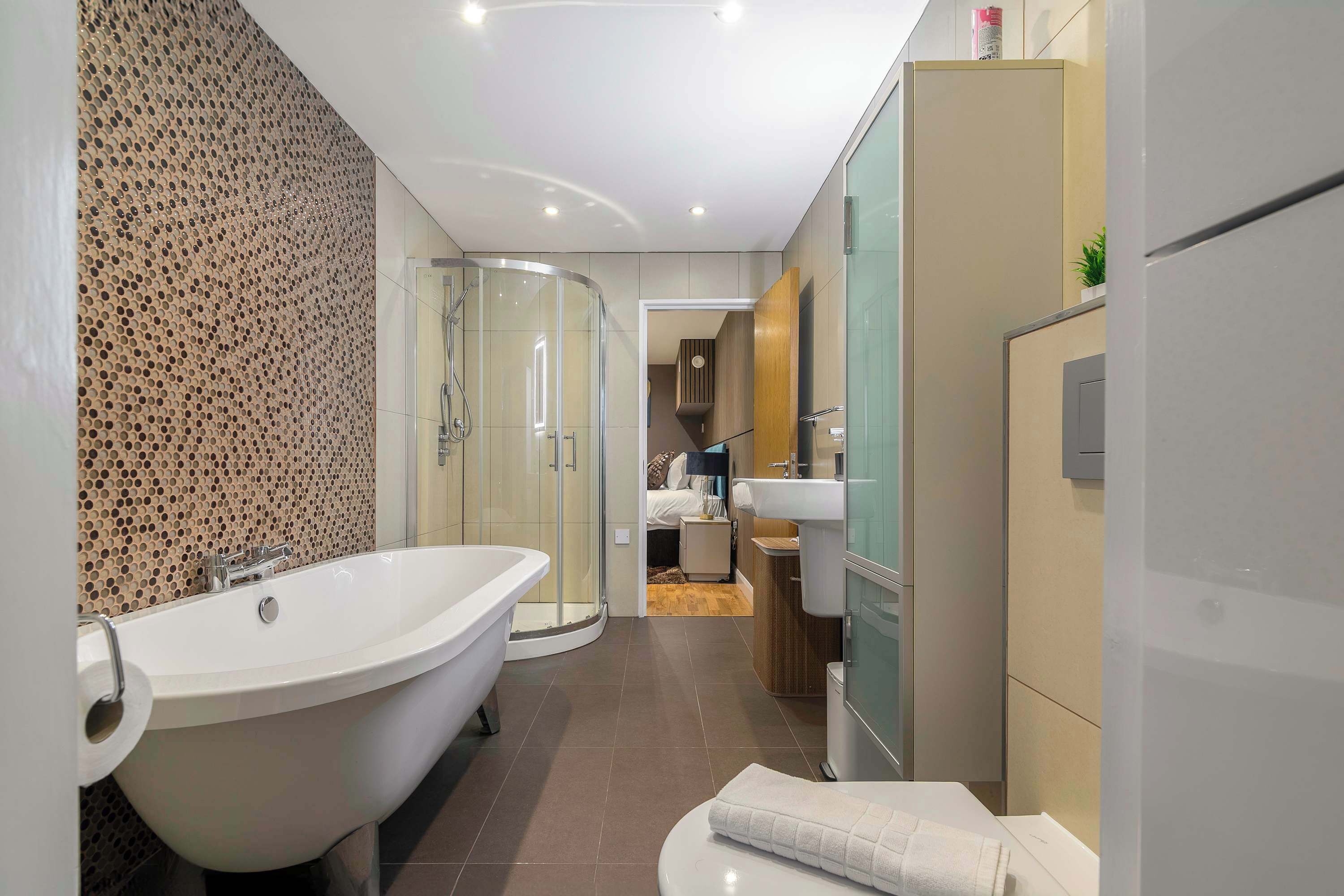 Een moderne badkamer met een vrijstaand bad, een douche met glazen wanden en een wastafelmeubel met spiegel.